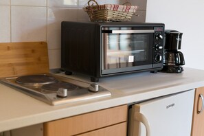 Een koelkast, een oven, een kookplaat, een eettafel