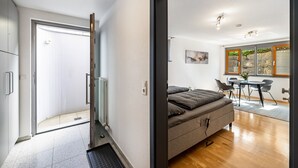 A modern bedroom with a bed, a radiator, a door, and a view of a dining area.