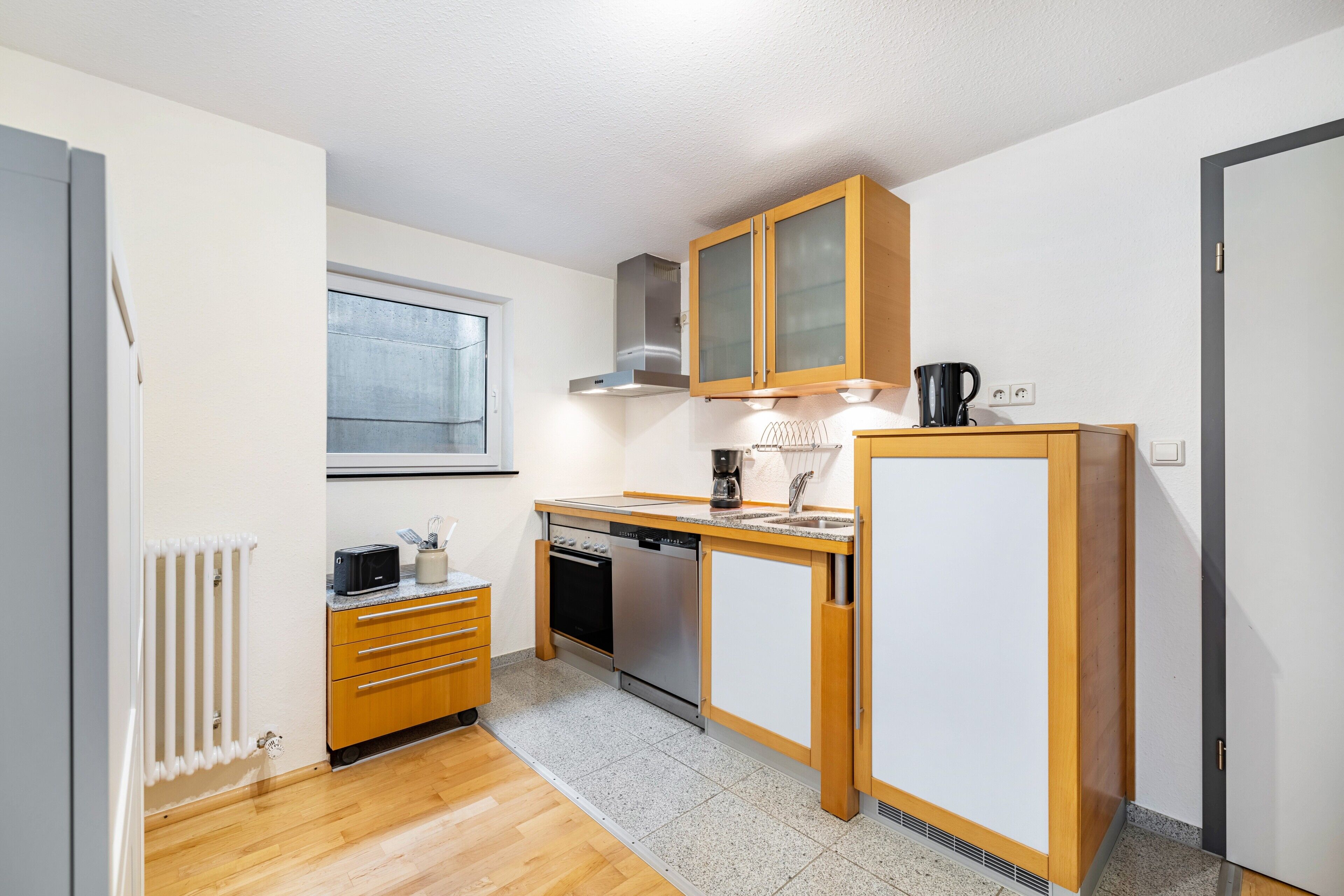A compact kitchen with wooden cabinets, a built-in oven, and a dishwasher.