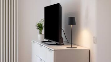 A flat-screen TV on a white cabinet with a black lamp beside it.