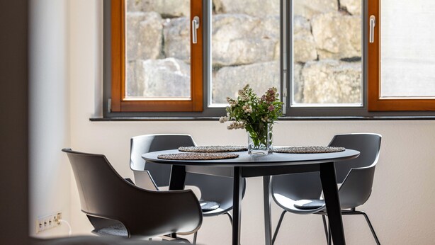 A dining area with a table, chairs, and a vase of flowers.