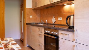 A modern kitchen with wooden cabinets, a stainless steel range hood, a kettle, and a tiled backsplash. - Apartment 'Nr 2' with Shared Garden, Balcony and Wi-Fi (Bad Peterstal-Griesbach)