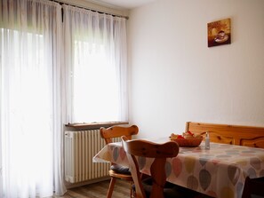 A room with a dining table, chairs, a radiator, and a window with sheer curtains. - Apartment 'Nr 1' with Shared Garden, Balcony and Wi-Fi (Bad Peterstal-Griesbach)