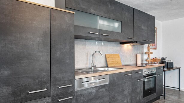 A modern kitchen with dark cabinetry, a stainless steel sink, and a built-in oven. - Apartment 'Sonnenseite' with Private Terrace and Wi-Fi (Ihringen am Kaiserstuhl)