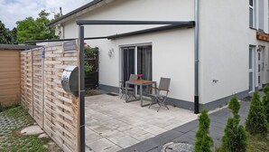 A patio with a table and chairs, a mailbox, and a wooden fence. - Apartment 'Sonnenseite' with Private Terrace and Wi-Fi (Ihringen am Kaiserstuhl)