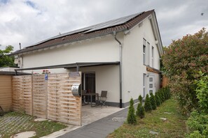 Un immeuble résidentiel doté d’un patio couvert, d’une clôture en bois et d’un petit jardin.