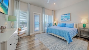 Een slaapkamer met een bed, twee nachtkastjes, een bureau, een stoel en een raam met zonwering.