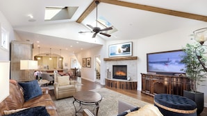 Un amplio salón con chimenea, televisión y ventilador de techo.