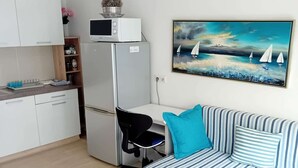 Ein kompakter Wohnraum mit Küchenzeile, Essbereich und einer Couch mit gestreiften Kissen.