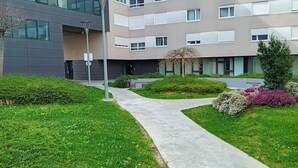 Ein modernes Gebäude mit flachem Dach, großen Fenstern und einem gepflegten Garten mit einem Weg.