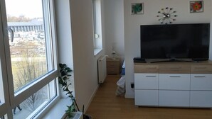 Ein modernes Wohnzimmer mit großem Fenster, einem Flachbildfernseher und minimalistischem Design.