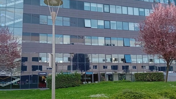 Ein modernes Gebäude mit Glasfassade, einer Straßenlaterne und einem gepflegten Rasen.