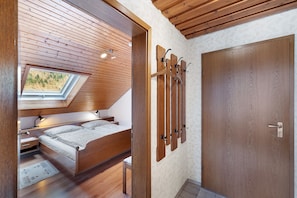 A bedroom with a skylight, wooden ceiling, and a bed with a nightstand.
