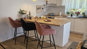 Una cocina moderna con una isla central, taburetes de bar y un comedor.