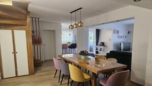 Un comedor moderno con una mesa de madera, sillas coloridas e iluminación colgante.