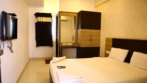 A hotel room with a bed, a TV mounted on the wall, a wardrobe, and a mirror. - SP Residency (Pollachi)