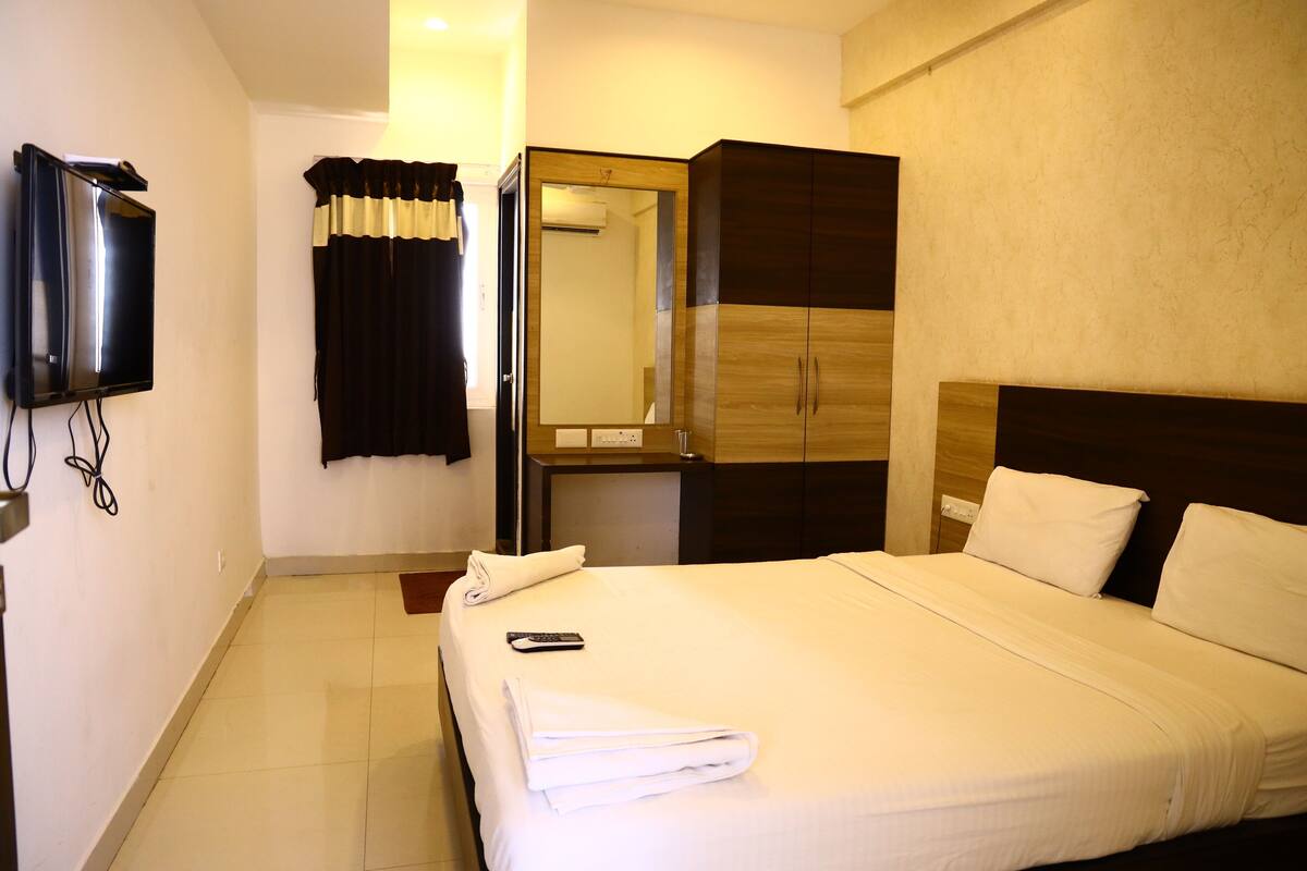 Une chambre d’hôtel comprenant un lit, un téléviseur fixé au mur, une armoire et un miroir.
