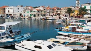 A marina with various boats docked, a clear sky, and colorful buildings in the background.