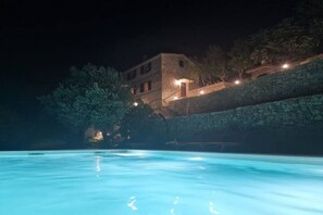 A stone building with a pool at night, surrounded by trees and a stone wall. - Stone House Bay View Kaštela - Two Bedroom House with Pool (Kastel Luksic)