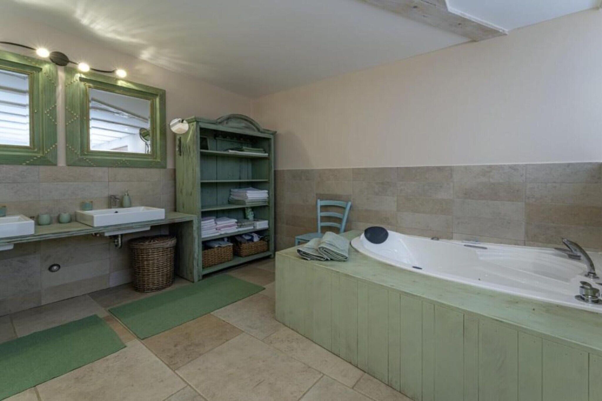 Ein Badezimmer mit Badewanne, zwei Waschbecken, einem Spiegel, Regalen mit Handtüchern und einem Korbwäscheschrank.