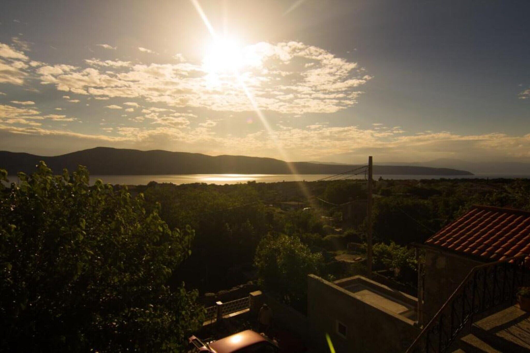 A sunset view over a body of water with distant mountains and a bridge.
