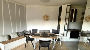 A modern living space with a sofa, dining table, and chairs. A kitchen area is visible in the background. - Modern & Charming - Free Private Parking - One Bedroom Apartment (Zagreb)