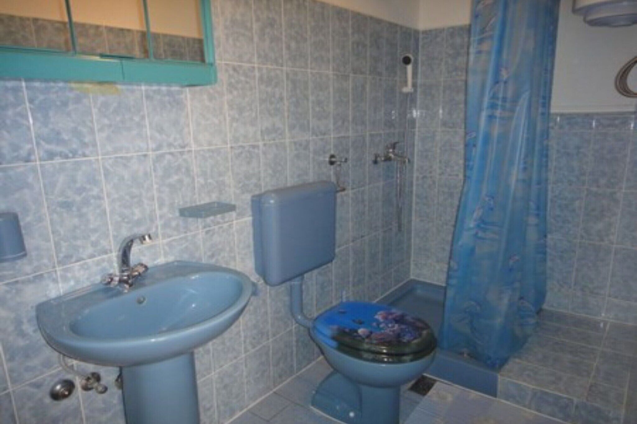 Et badeværelse med vask, toilet og badeforhæng.