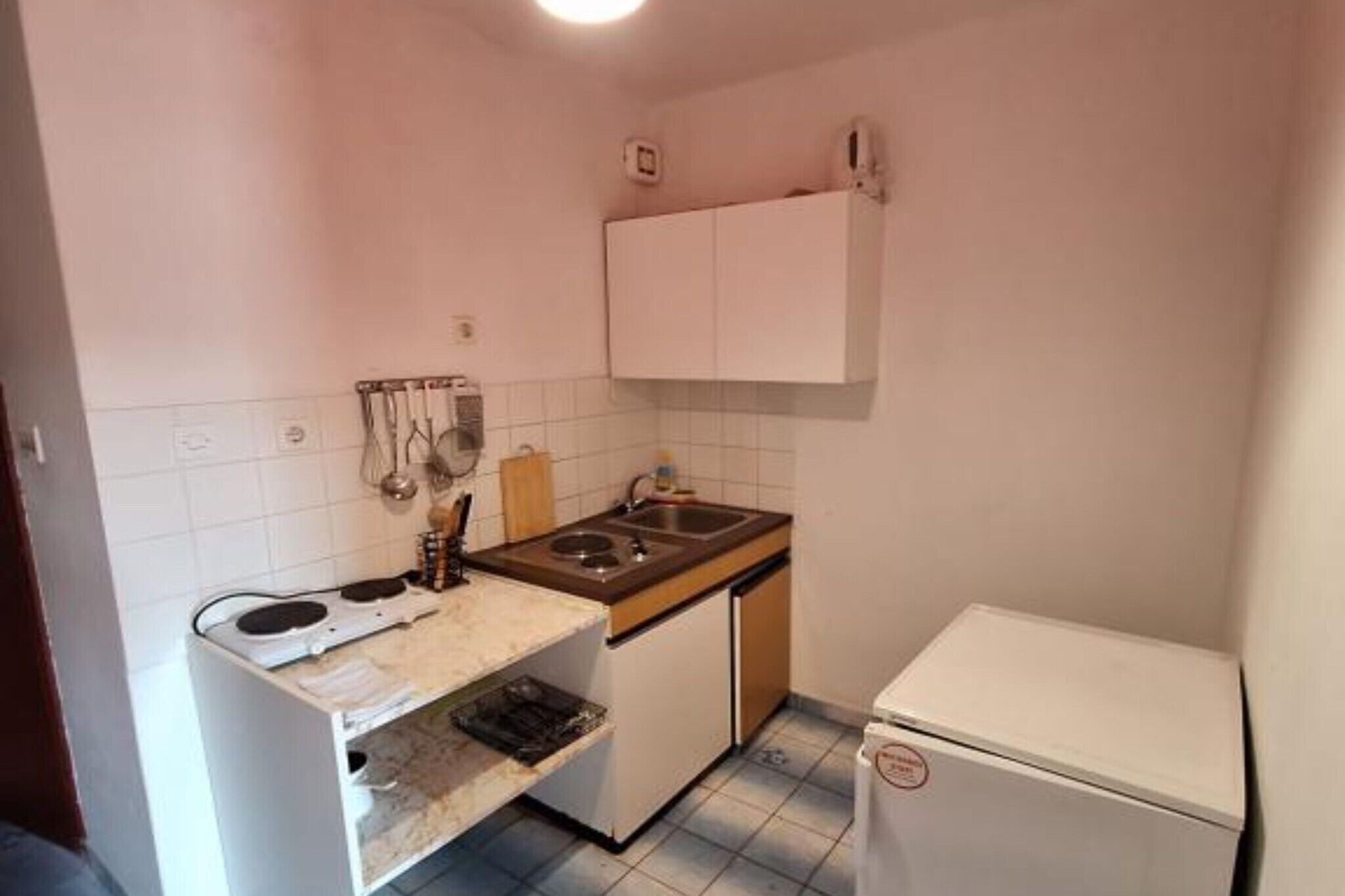 A compact kitchen with a stove, sink, and white cabinets.