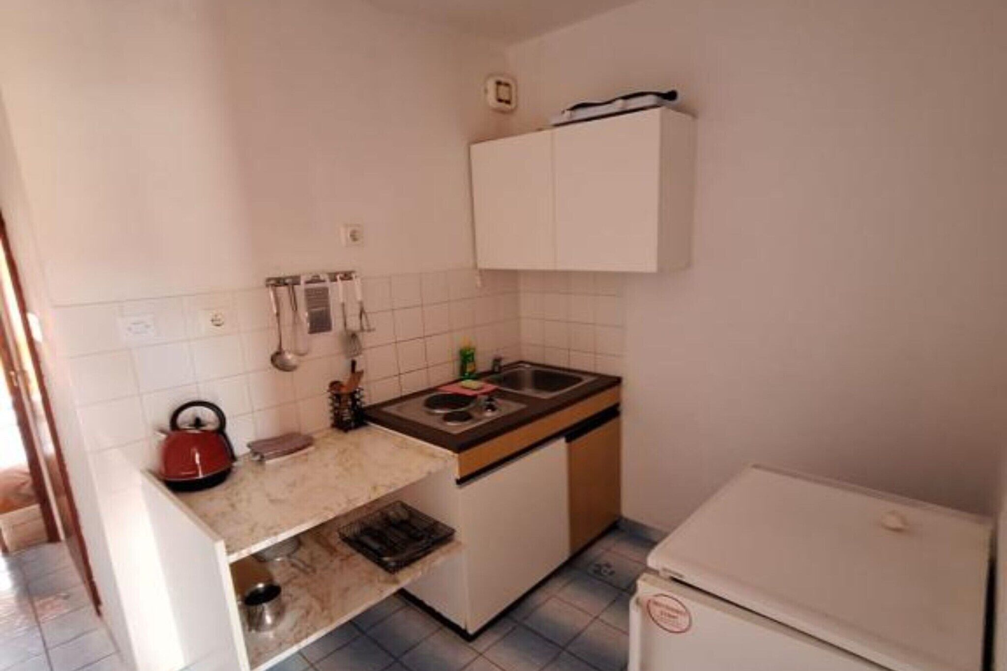 A small kitchen with white cabinets, a sink, and a stove.