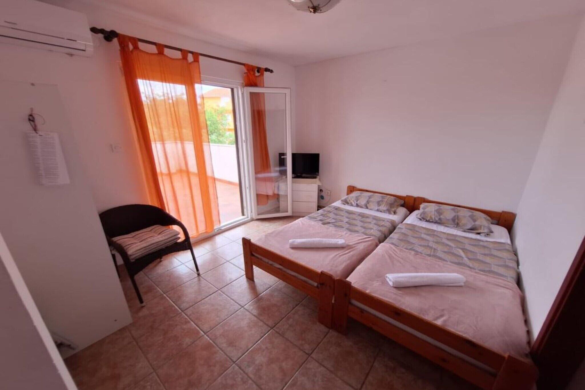 Un dormitorio con dos camas, una silla, un televisor y un ventanal corredizo al exterior.