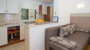 A compact living space with a kitchenette, a sofa with patterned cushions, and a wall-mounted clock. - Sea View Apartments Lendic Podgora - Classic Studio Apartment with Terrace and Sea View (Podgora)