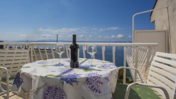 A balcony with a table set for two, a bottle of wine, and a view of the sea. - Sea View Apartments Lendic Podgora - Classic Studio Apartment with Terrace and Sea View (Podgora)