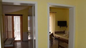 A room with a bed, a television, and a window with curtains.
