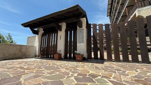 Una entrada con suelo de piedra, un portón de madera y una estructura de pérgola.