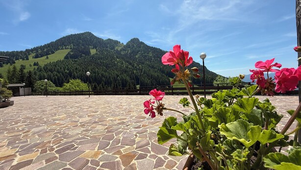 Una terraza empedrada con vistas a una cadena montañosa y una valla de madera.