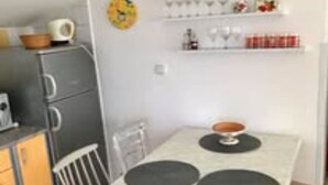 A compact kitchen with a dining table, a microwave, and a small refrigerator. - Apartment Belu - Two Bedroom Apartment With Sea View (Brodarica)