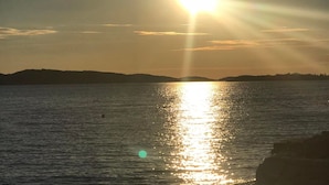 A sunset over a body of water with distant landforms. - Apartment Belu - Two Bedroom Apartment With Sea View (Brodarica)