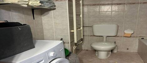 Un baño pequeño con lavadora, inodoro y radiador.