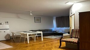Un espacio habitable compacto con comedor, sofá, una silla, refrigerador y ventana con cortinas.