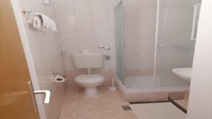 A bathroom with a toilet, bidet, and a glass-enclosed shower.