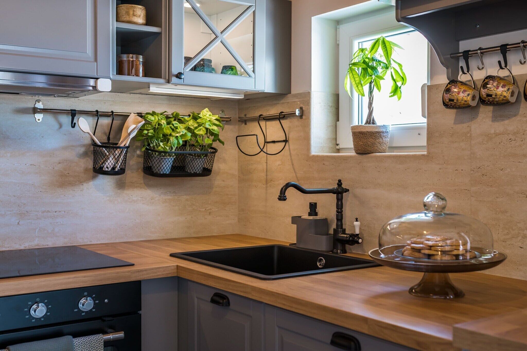 A kitchen with a black sink, wooden countertop, and a window with a potted plant.