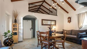 A dining area with a wooden table and chairs, a mirror above, and a staircase with exposed beams.