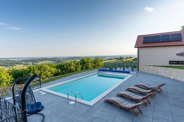 A swimming pool with lounge chairs and a view of the countryside. - Villa Breg - Four Bedroom Villa with Pool, Hot-Tub and Sauna (Križevci)
