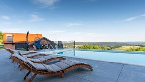 A swimming pool with lounge chairs and a house in the background. - Villa Breg - Four Bedroom Villa with Pool, Hot-Tub and Sauna (Križevci)