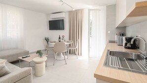 Eine moderne Küche mit Spüle, ein Essbereich mit Tisch und Stühlen sowie eine Wohnbereich mit Sofa und Couchtisch.