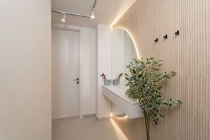 A modern bathroom with a white vanity, a large mirror, and a potted plant.