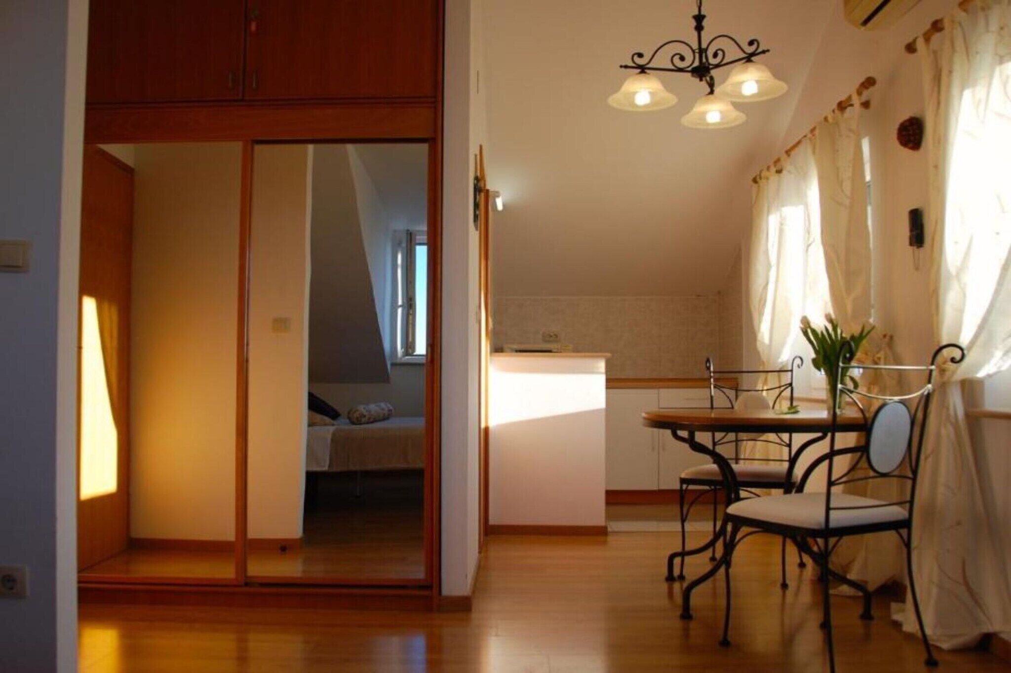 A compact kitchen with a dining area, a sliding door leading to a bedroom, and a chandelier.