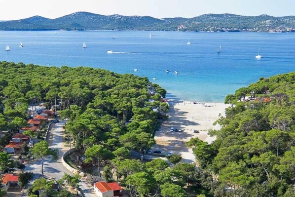Una zona costera con playa, barcos y una carretera que lleva a un conjunto de edificios.