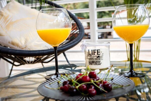 Two glasses of orange juice on a glass table with a glass candle and cherries.