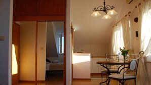 Kompakti keittiö, jossa on ruokailutila, liukuovi, joka johtaa makuuhuoneeseen, ja kattokruunu.